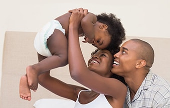Mother and father holding baby in diaper