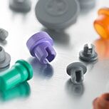 Pharmaceutical stoppers in grey, orange, and purple