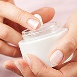 Skin care cream being removed by a hand.