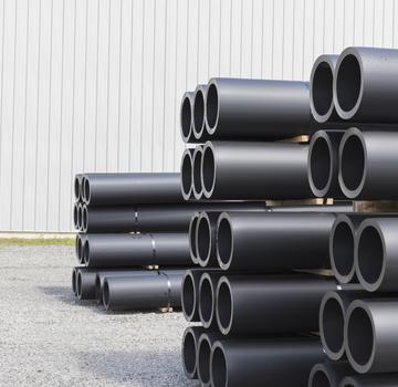 Tuberías industriales de PVC apiladas frente a una planta de fabricación