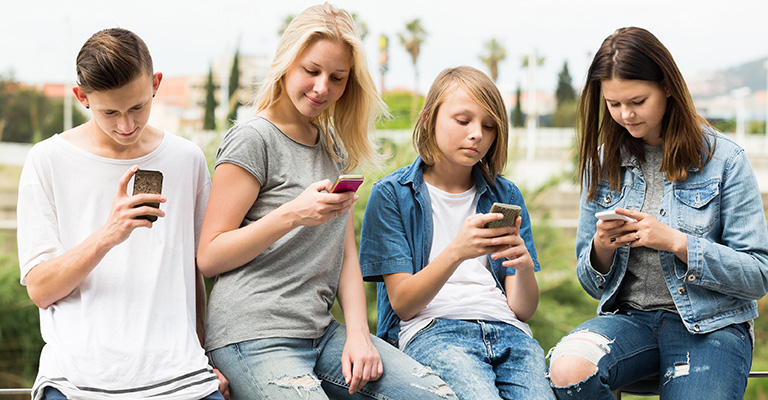 Adolescentes en sus teléfonos celulares.